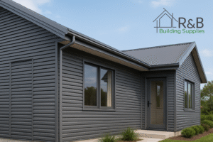 A modern house with gray siding and a metal roof. Black-framed windows and a glass door accentuate the design. Logo reads "R&B Building Supplies."